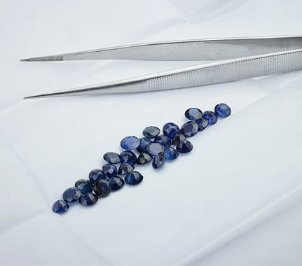 Parcel of loose blue sapphires with gemstone tweezers