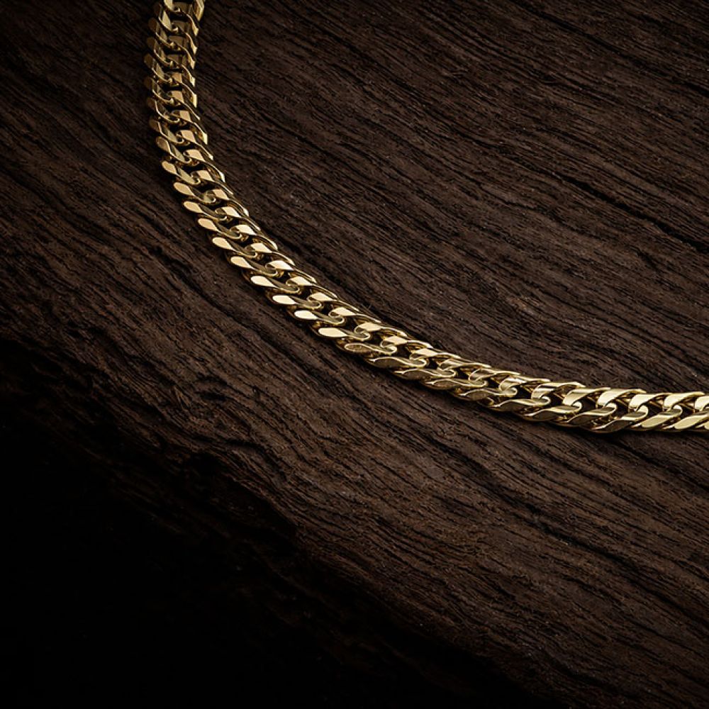 Pre-Loved 22 inch gold curb chain close up view of links on wood background