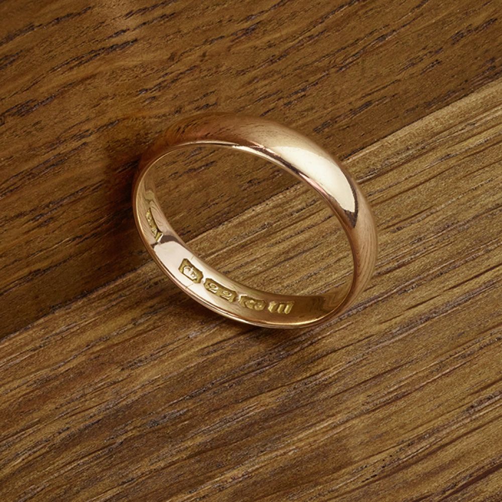 22ct Gold 1912 vintage wedding ring shown on wood background