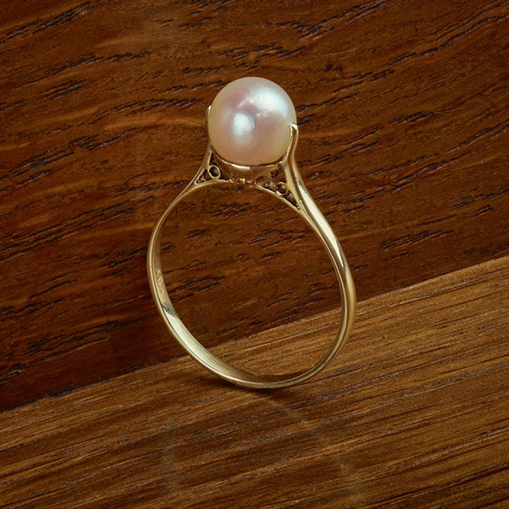 Solitaire Gold Vintage Pearl Ring on Wood Background